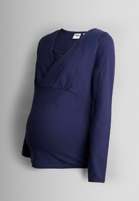 Blusa de maternidad de manga larga en azul marino, con un diseño envolvente, detalles fruncidos en la cintura y una textura de tela suave.