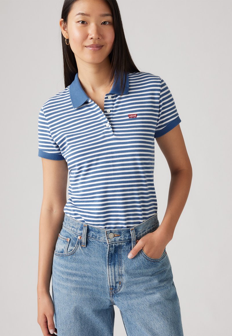 Ριγέ πόλο μπλουζάκι σε μπλε και λευκό με κουμπωτό γιακά και λογότυπο Levi's. Συνδυασμένο με ανοιχτό μπλε ψηλόμεσες τζιν. 
