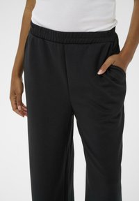 Sort, løstsiddende bukser lavet af blødt stof med elastisk talje og sidelomme. Glat tekstur og lige ben-design.