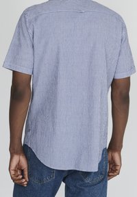 Lyhyet hihnat, sinivalkoisilla pystysuorilla raidoilla, pyöreällä helmalla, pehmeällä tekstuurilla ja rento istuvuus. Kevyt kangas.