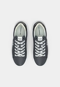Γκρι δερμάτινα αθλητικά παπούτσια με λευκά κορδόνια και γκρι λεπτομέρεια στη φτέρνα. Διαθέτουν λογότυπο στη γλώσσα και σχεδιασμό με λείο, στρογγυλεμένο μπροστινό μέρος.