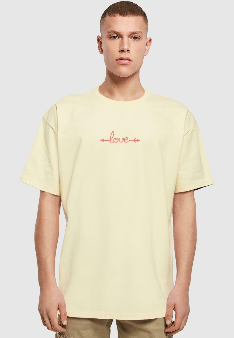 Világos sárga pamut póló középen vörös "love" grafikával, nyilakkal, laza fazonban, rövid ujjal és kerek nyakkivágással.