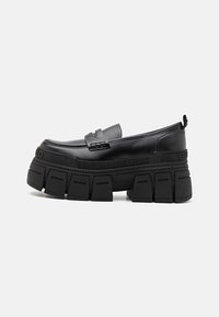 Mustad mustad loafers, mis on valmistatud siledast nahast ja millel on paks ja tükkis tall. Omab lihtsat rihma ja graveeritud brändingut küljel.