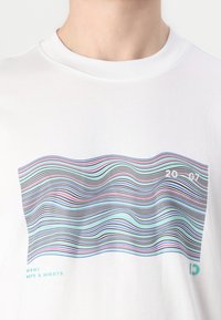 Witte katoenen T-shirt met een golvende, multicolore lijnprint in tinten blauw, roze en zwart, met de tekst "MIAMI" en "DAYS & NIGHTS".
