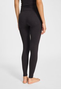 Czarne legginsy wykonane z elastycznego materiału, z wysokim pasem i teksturowanym wzorem. Logo umieszczone w pobliżu kostki.