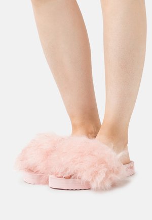 Fluffy pink slides with a textured upper, featuring a wide strap and a thick, soft sole. The footwear has a casual, open-toe design.