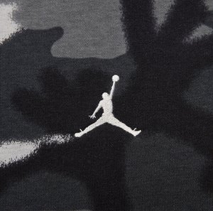 Kamouflage-mönstrad tyg i grå nyanser har en vit broderad Jumpman-logotyp, vilket framhäver atletisk rörelse och dynamisk design.
