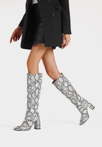 Stivali alti fino al ginocchio realizzati in materiale a stampa serpente bianco e nero, con tacco a blocco e finitura liscia.