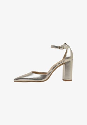 Zapato de tacón alto metálico plateado con punta afilada, correa en el tobillo y tacón grueso, mostrado de perfil sobre fondo blanco.