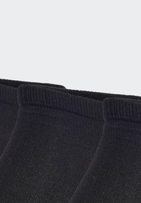 Calcetines de algodón negros hasta el tobillo con textura acanalada y puños reforzados, que presentan un acabado suave y sin logotipos ni adornos visibles.