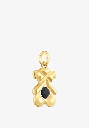 Ciondolo a forma di orsetto in tonalità oro con superficie lucida, caratterizzato da una gemma nera centrale. Include un anello per l'attacco.