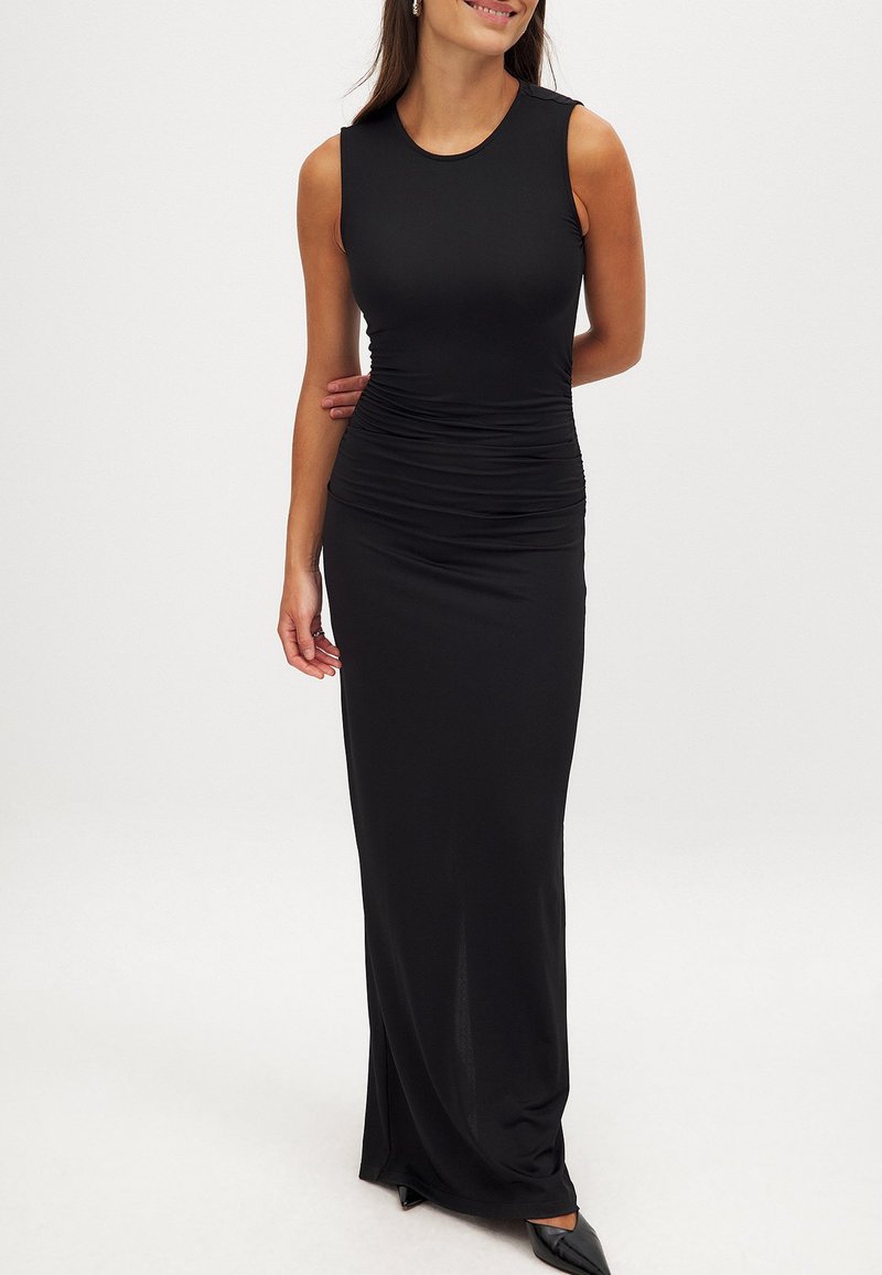 Mustra mustriga, varvitud detailidega ja sobiva siluetiga musta varrukateta maxi kleit, valmistatud siledast, venivast kangast, ulatudes pahkluudeni.