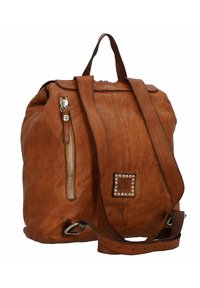 Brauner Leder-Rucksack mit einem Reißverschlussfach, quadratischem dekorativem Anhänger mit Nieten und verstellbarem Schulterriemen. Texturierte Oberfläche und weiche Kanten.