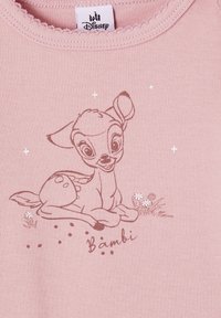 Pink cotton shirt featuring a printed illustration of Bambi lying down, with white floral details and the name "Bambi" in a playful font.