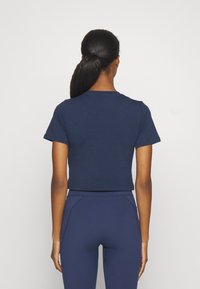Cropped navy blue T-shirt with short sleeves and a round neckline, made from soft fabric. Paired with matching navy pants.