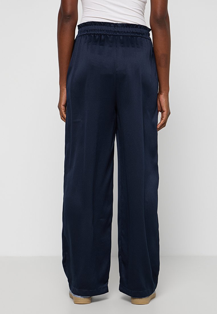 Marineblaue weite Hosen aus einem strukturierten, glatten Stoff mit einem elastischen Bund. Sie verfügen über eine lockere Passform und einen geraden Saum.