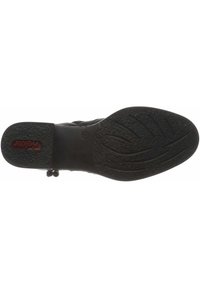 Zapato de cuero negro con suela texturizada, que presenta una punta redonda, parte superior lisa y acentos de botón en el costado para el cierre.