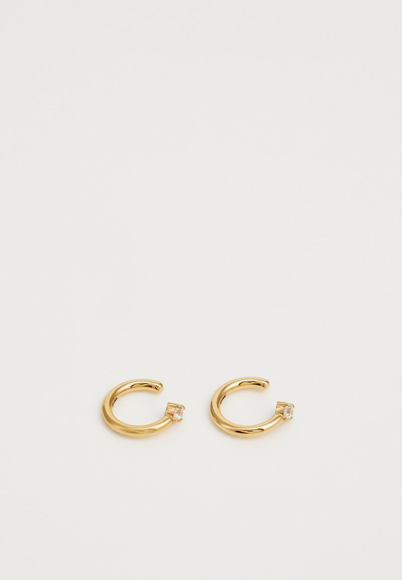 Boucles d'oreilles en or en forme de créole avec une finition lisse et un petit accent en cristal à une extrémité. Forme circulaire, design minimaliste et texture brillante.