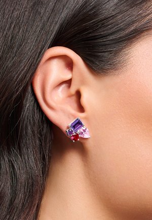Mehrfarbige Ohrringe mit rechteckigen lila, rosa und roten Steinen aus Silbermetall, die nahe dem Ohrläppchen befestigt sind.