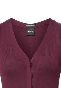 Bordeaux ribbel gebreide cardigan met een diepe V-hals, voorste knoopsluiting en labels "SUPERFINE MERINO" en "BOSS". Zachte textuur.