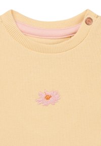 Ribbed yellow fabric top with a round neckline, featuring a pink embroidered flower design and a small button detail at the shoulder.