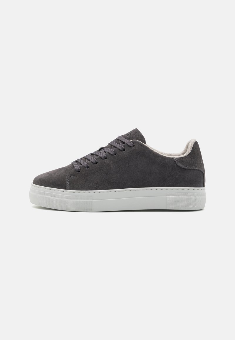 Zapatillas de ante gris oscuro con puntera redonda, cordones planos y suela de goma blanca. Textura suave con detalles de costura mínimos y acolchado en el tobillo.