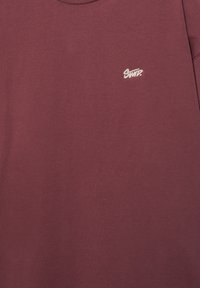 Sweatshirt bordeaux à col rond avec petit logo "SWT?" blanc brodé sur la poitrine gauche.
