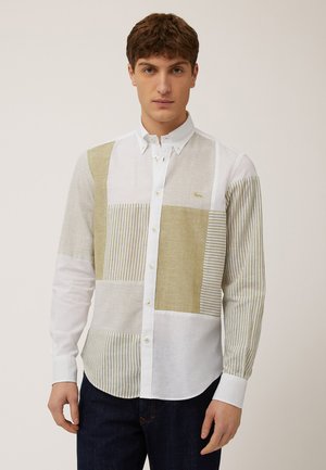 White button-up shirt featuring a patchwork design with beige and light green striped sections. Made of cotton, it has a smooth texture.