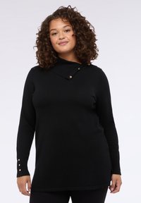 Svart långärmad tröja med hög krage, med en diagonalt panel och guldknappar. Mjuk material och avslappnad passform, med sidofickor.