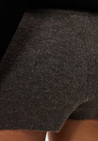 Σκούρα γκρι πλεκτές βερμούδες με απαλό υφή. Διαθέτουν εφαρμοστή σχεδίαση με ελάχιστες ραφές και μικρές πλευρικές σχισμές για άνεση.