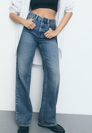 Hoog-rug wijde jeans in mediumblauwe denim met een vervaagde afwerking, met een knoopsluiting en gedetailleerde stiksels op de zakken.