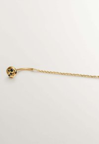 Pendiente de cadena dorada con un gancho curvado y un disco redondo que presenta cuatro piedras negras de acento. Textura suave y acabado pulido visible.