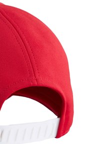 Czerwona czapka bejsbolowa z zaokrągloną koroną i widocznym szwem; z tyłu posiada białą regulowaną taśmę do dopasowania rozmiaru.