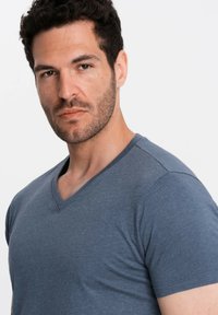 Šedé tričko s výstřihem do V vyrobené z měkké, strukturované tkaniny, se slim fit střihem a krátkými rukávy, obsahující jemný melírovaný vzor a čistý výstřih.