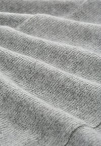 Grauer Stoff mit einer weichen, strukturierten Oberfläche, der sanft gefaltete Schichten zeigt, die seine leichte und elastische Beschaffenheit betonen.