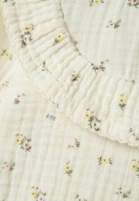 Katoenen stof met kleine pastelbloemenpatronen; heeft een gestructureerde, geplooide ruffle-afwerking langs de rand in zachte witte tinten.