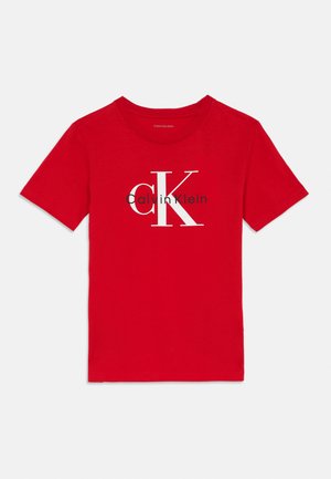Punane lühikeste varrukatega T-särk, millel on suur valge "cK" ja must "Calvin Klein" logo esiküljel keskel.