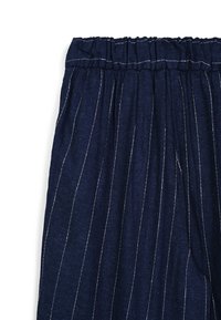 Pantalons bleu marine avec des rayures verticales blanches, dotés d'une taille élastique et d'une texture douce. Aucune poche visible sur l'image.