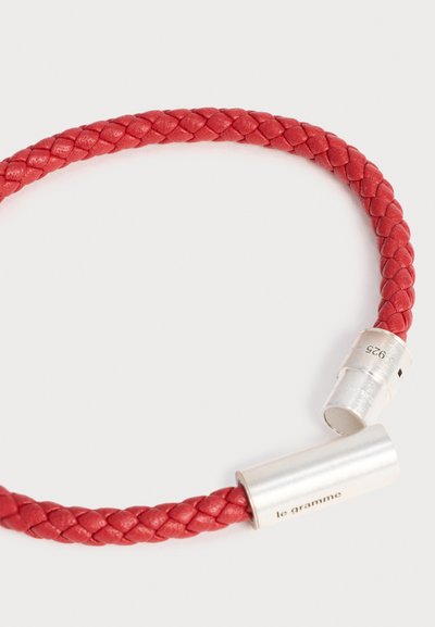 Bracelet en cuir tressé rouge avec fermoir cylindrique en argent gravé des inscriptions « le gramme » et « 925 ».