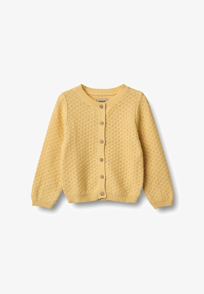 Keltainen neulecardigan, jossa on teksturoitu kuvio, pyöreä kaula-aukko ja nappikiinnitys edessä. Sisältää pitkät hihat ja ribbikujat.