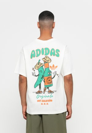 Hvitt bomull T-skjorte med et fargerikt grafisk motiv på baksiden som viser tegneserie jalapeño figurer, oransje detaljer og "ADIDAS" tekst.