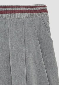 Graue, plissierte Hose aus einem strukturierten Stoff. Mit einem gerippten Bund, der rot-graue Streifen aufweist.