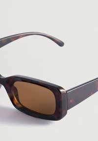 Pruun kilpkonnakujulised päikeseprillid laia ristküliku kujuga raamidega ja tumepruunide läätsedega. Sile plastmaterjal, millel on läikiv viimistlus.