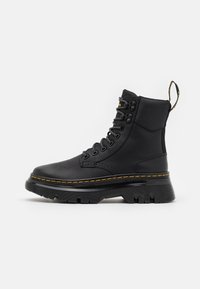 Botines de cuero negro hasta el tobillo con cuello acolchado, punta redonda, diseño con cordones, costuras amarillas y suela de goma texturizada.