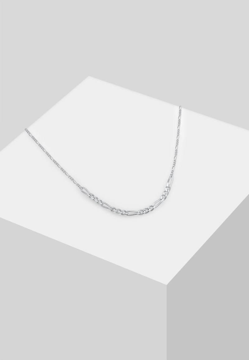 Collier chaîne en argent avec des maillons alternés ovales et plats, présenté sur un socle blanc sur fond gris clair.