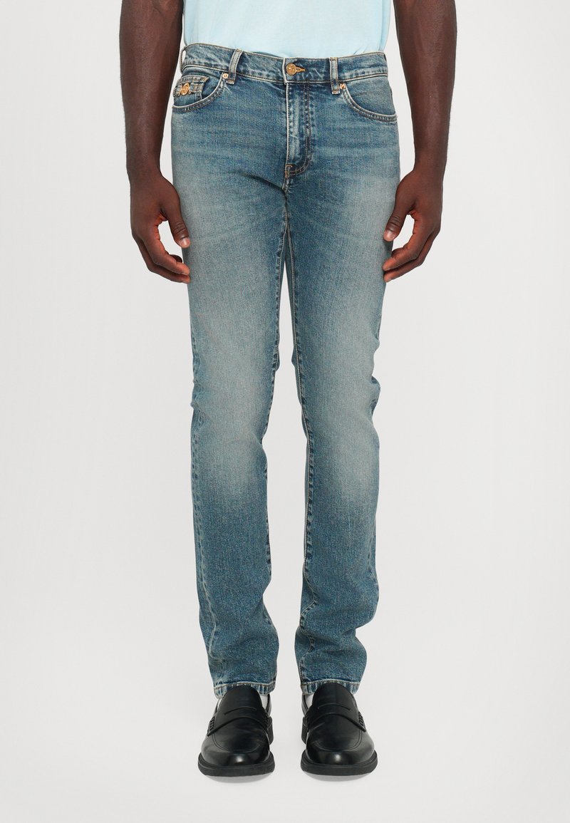 Light blue denim jeans with a straight fit, featuring five pockets, subtle fading, curved waistband, and a button fly.