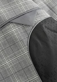 Textil de cuadros en tonos grises con un suave acento negro. Presenta un borde en contraste y un patrón texturizado en la sección negra.