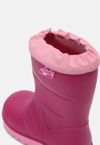 Botte de pluie enfant rose avec bord supérieur rembourré, semelle texturée et étiquette en tissu portant la mention "Lurchi" sur le côté.