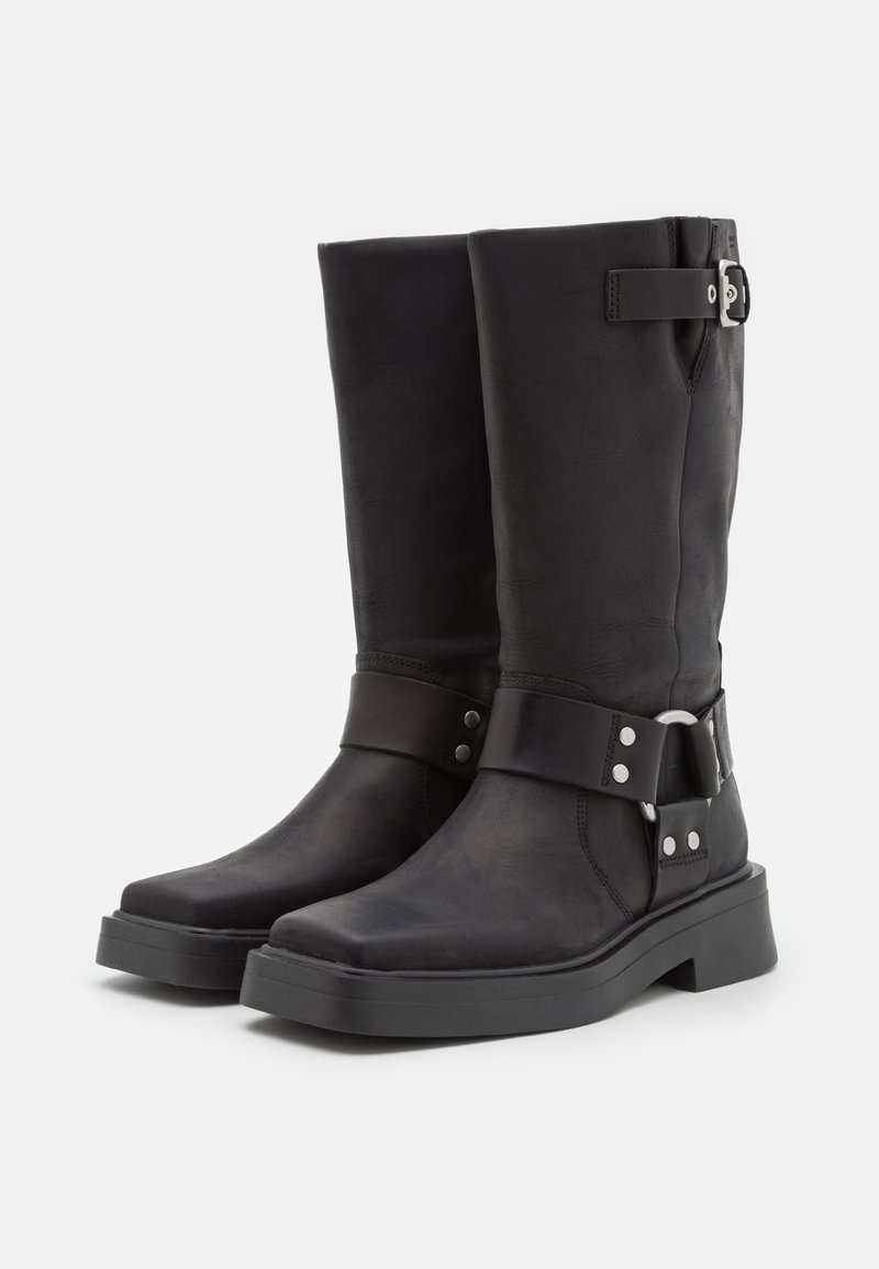 Schwarze Leder-Knielange Stiefel mit quadratischer Zehenform, Akzentriemen und silbernen Beschlägen, ausgestattet mit einer dicken Gummisohle für zusätzliche Stabilität.