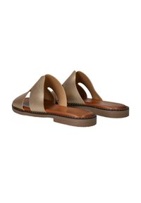 Een paar taupe platte sandalen met brede open banden en bruine gevoerde voetbedden, getoond vanuit de achterkant en een schuine zij-aanzicht.